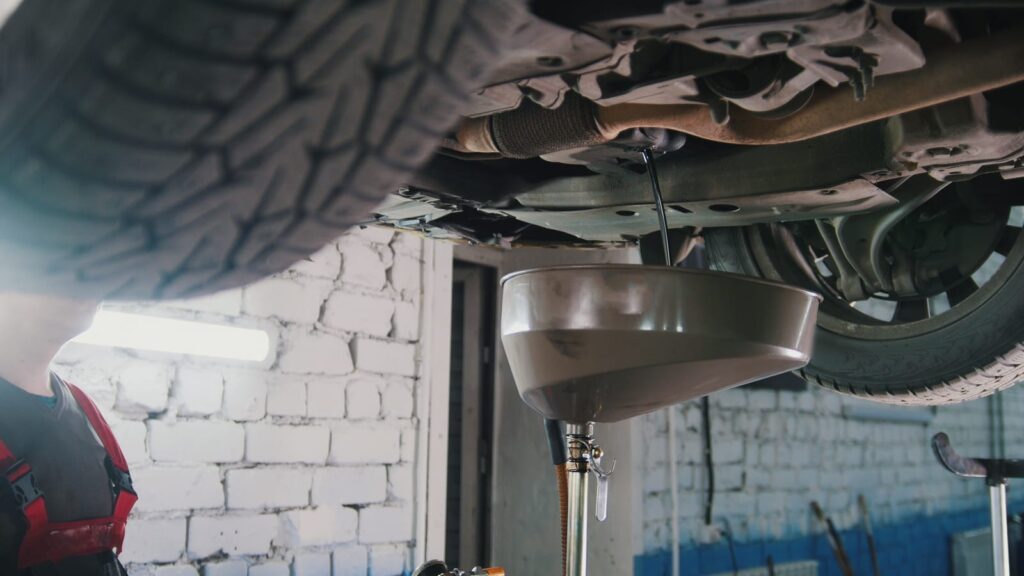 Oil change in progress: Used oil draining from a car's engine at America 1st Automotive.