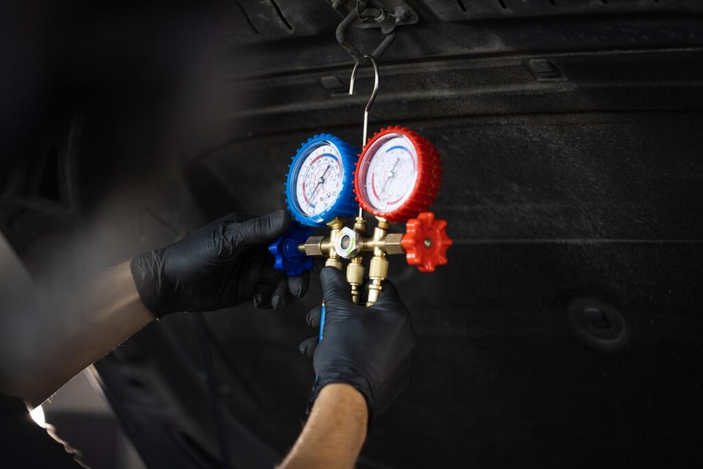 A mechanic checking the refrigerant in a vehicle