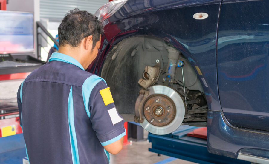 A repair technician performing a brake inspection on a car