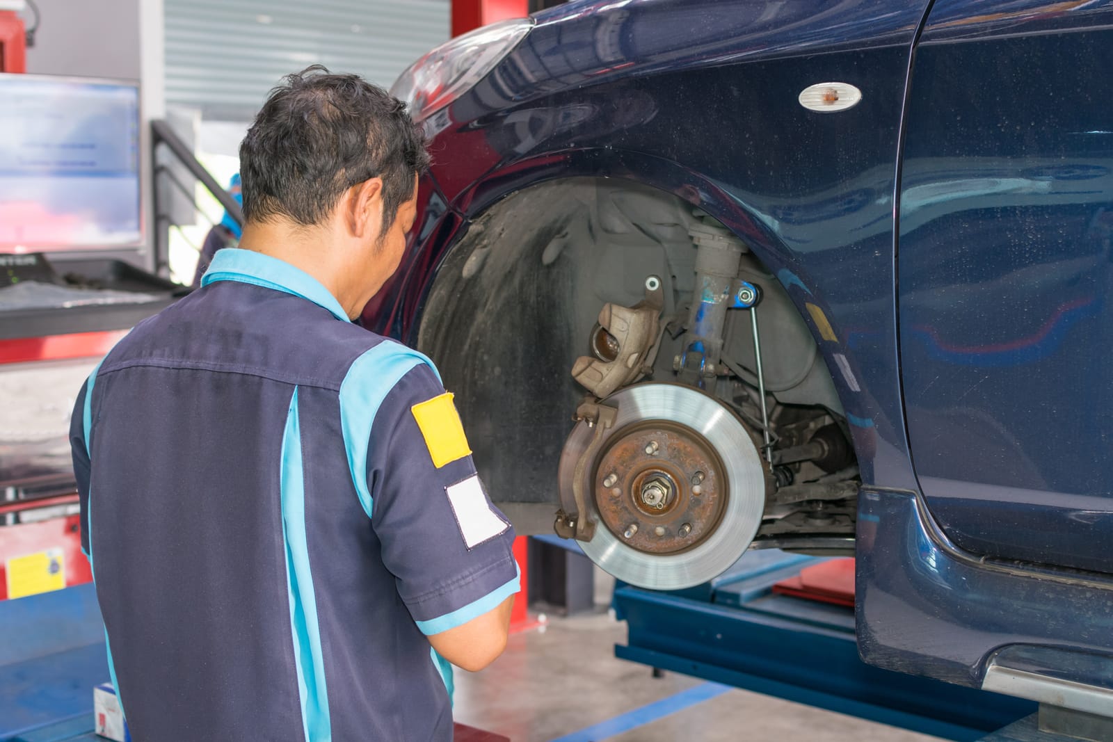 A repair technician performing a brake inspection on a car
