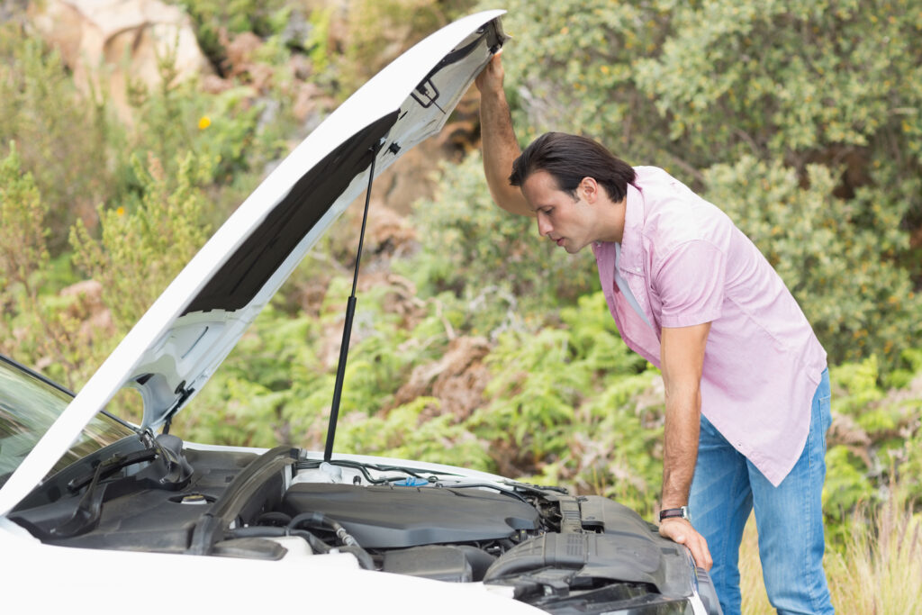 A man looking under the hood of his car