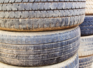 A photo of a stack of dirty old tires with diverse types and depth of tread