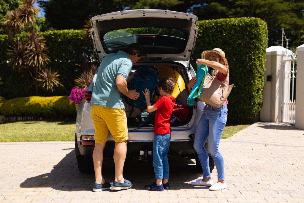 Happy family putting all their luggage in their car