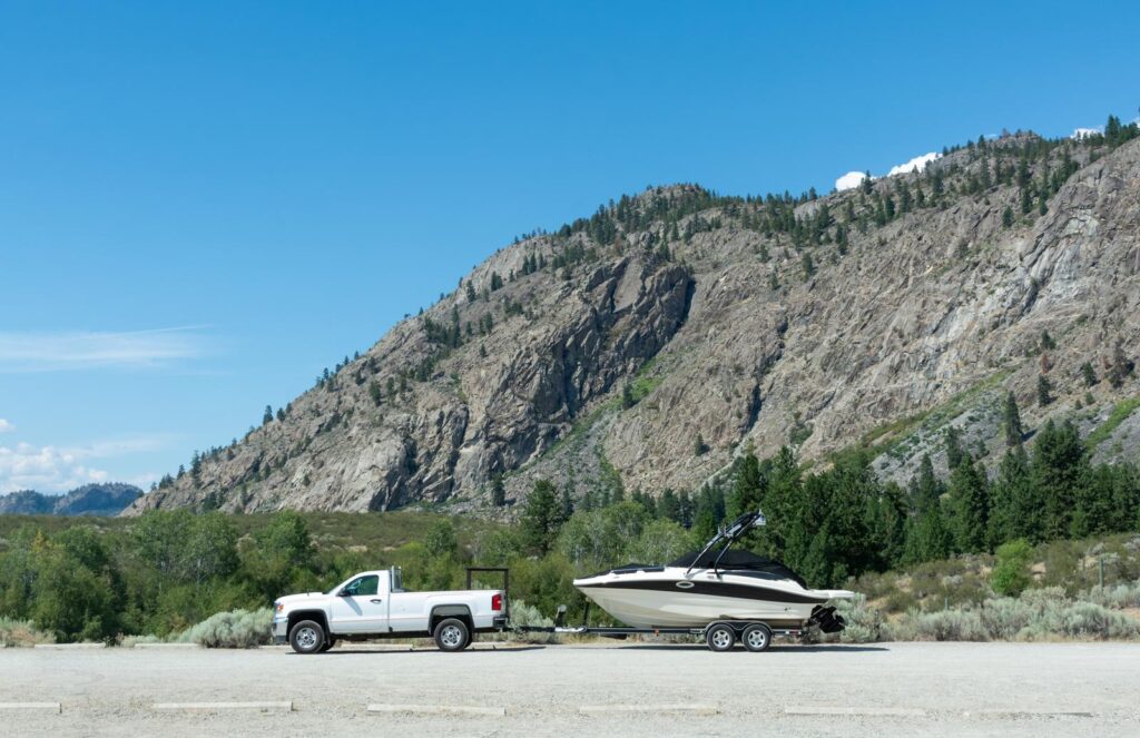 A white truck towing a boat to the water