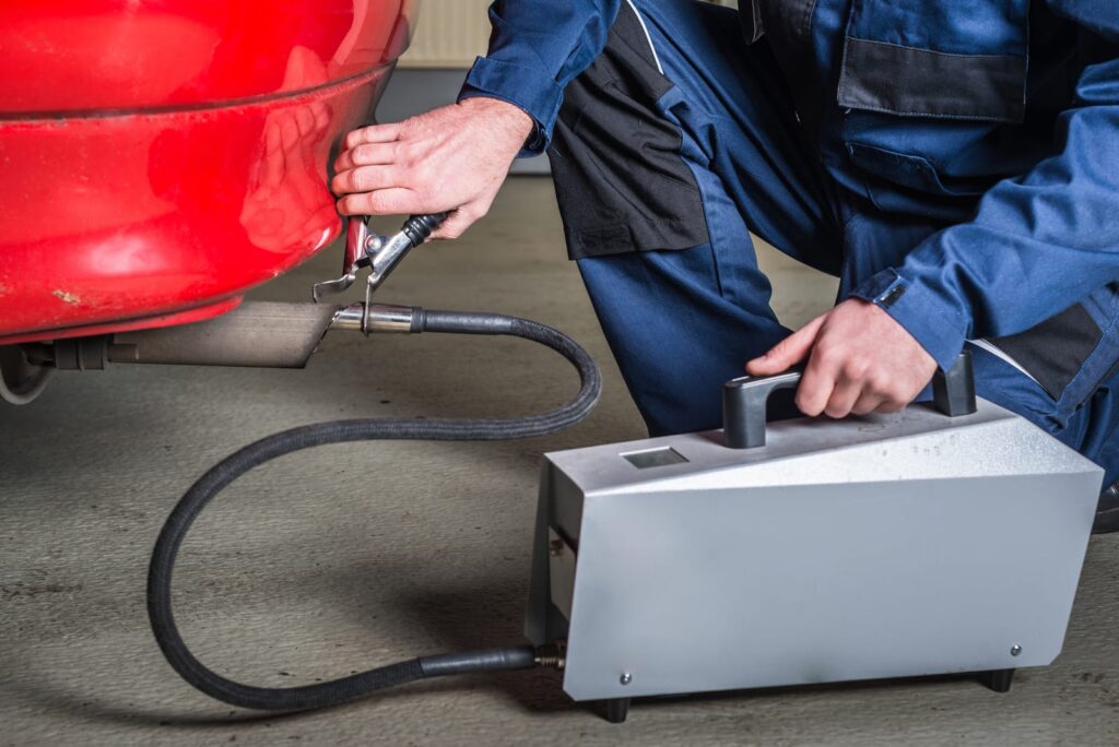 a Diagnostic Sensor Applied to the Exhaust of a Red Car Measuring the Composition and Substances in the Exhaust Fumes a diagnostic sensor applied to the exhaust of a red car measuring the composition and substances in the exhaust fumes