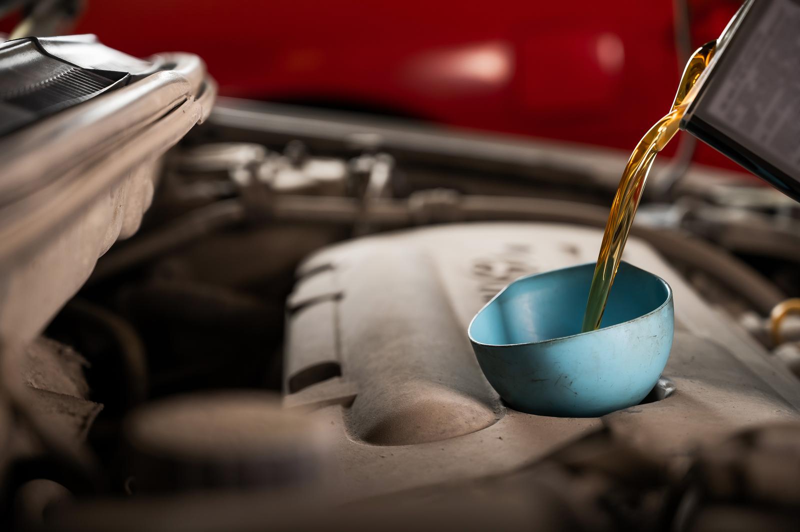 An Auto Mechanic Pours Oil Into a Car Engine