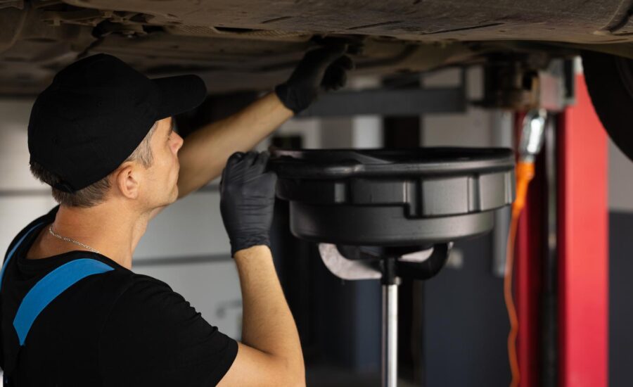 A mechanic drain the old oil from the engine through the drain plug Changing the oil in a car engine Car engine oil replacement Car maintenance car mechanic replaces the oil in the engine