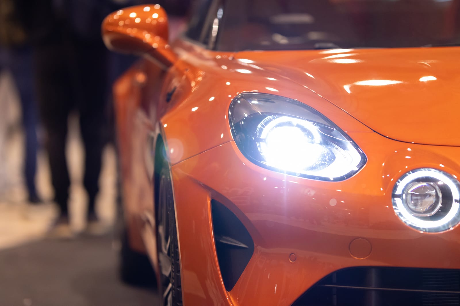 Orange sports car with its headlights on