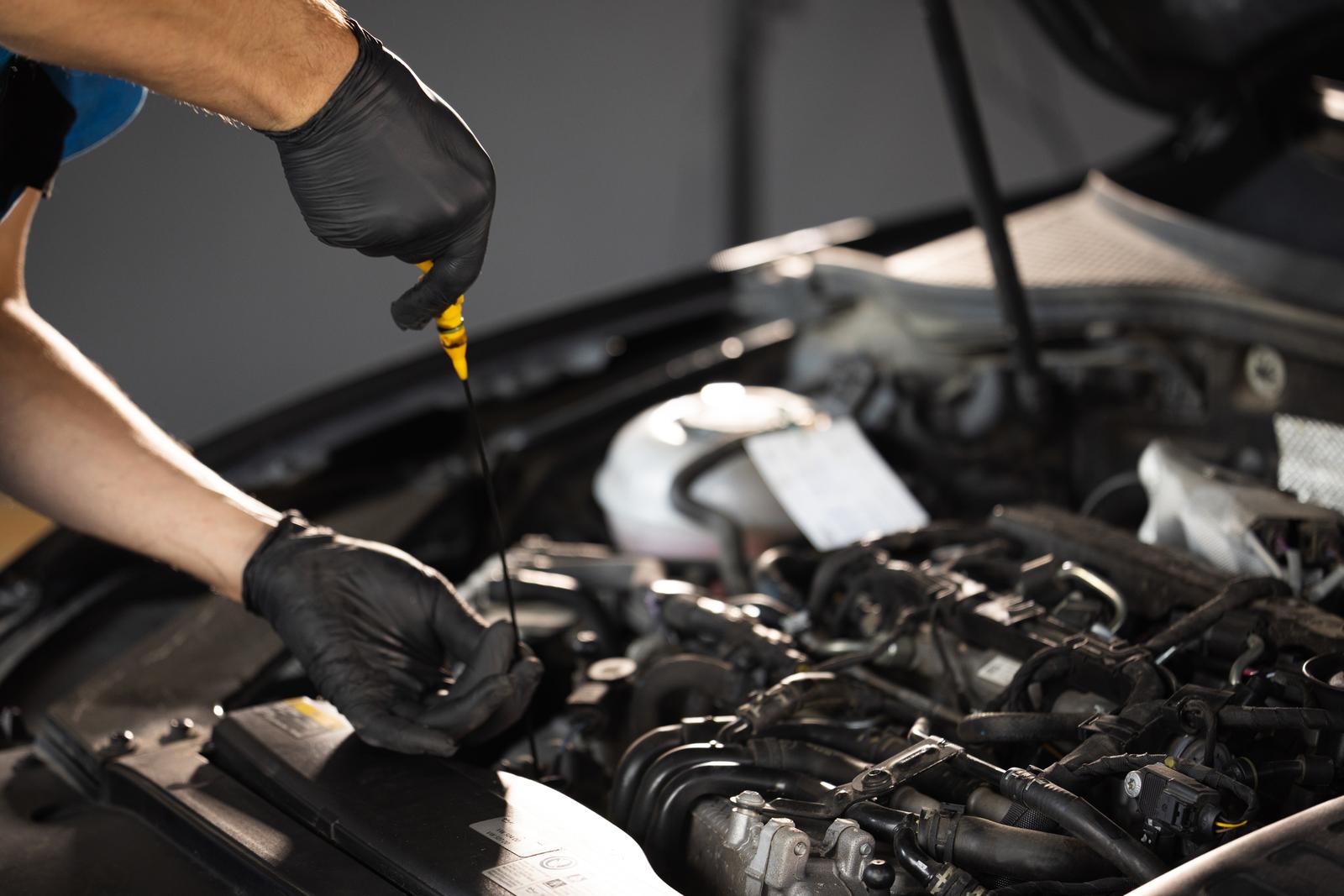 Close-up of automotive mechanic checks the oil level on the car engine dipstick