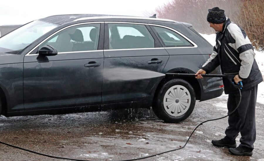 A man washes the dirt and salt off his car in winter
