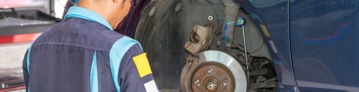 A repair technician performing a brake inspection on a car