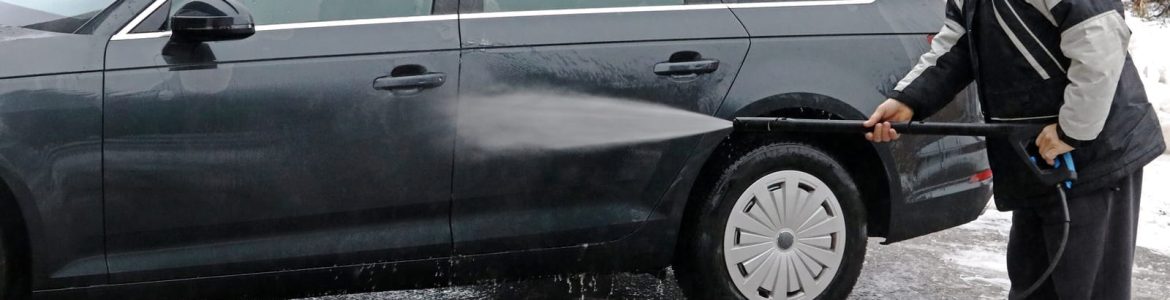 A man washes the dirt and salt off his car in winter
