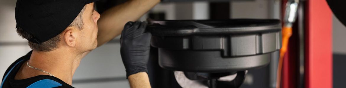 A mechanic drain the old oil from the engine through the drain plug Changing the oil in a car engine Car engine oil replacement Car maintenance car mechanic replaces the oil in the engine